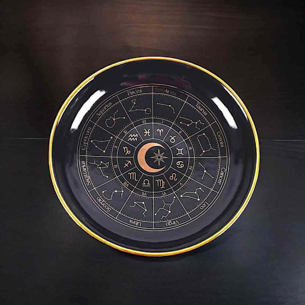 Black circular astrology jewellery dish with gold rim and zodiac constellation details