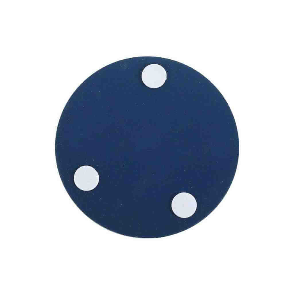 Round dark-blue coaster with three small white dots speckled on the surface