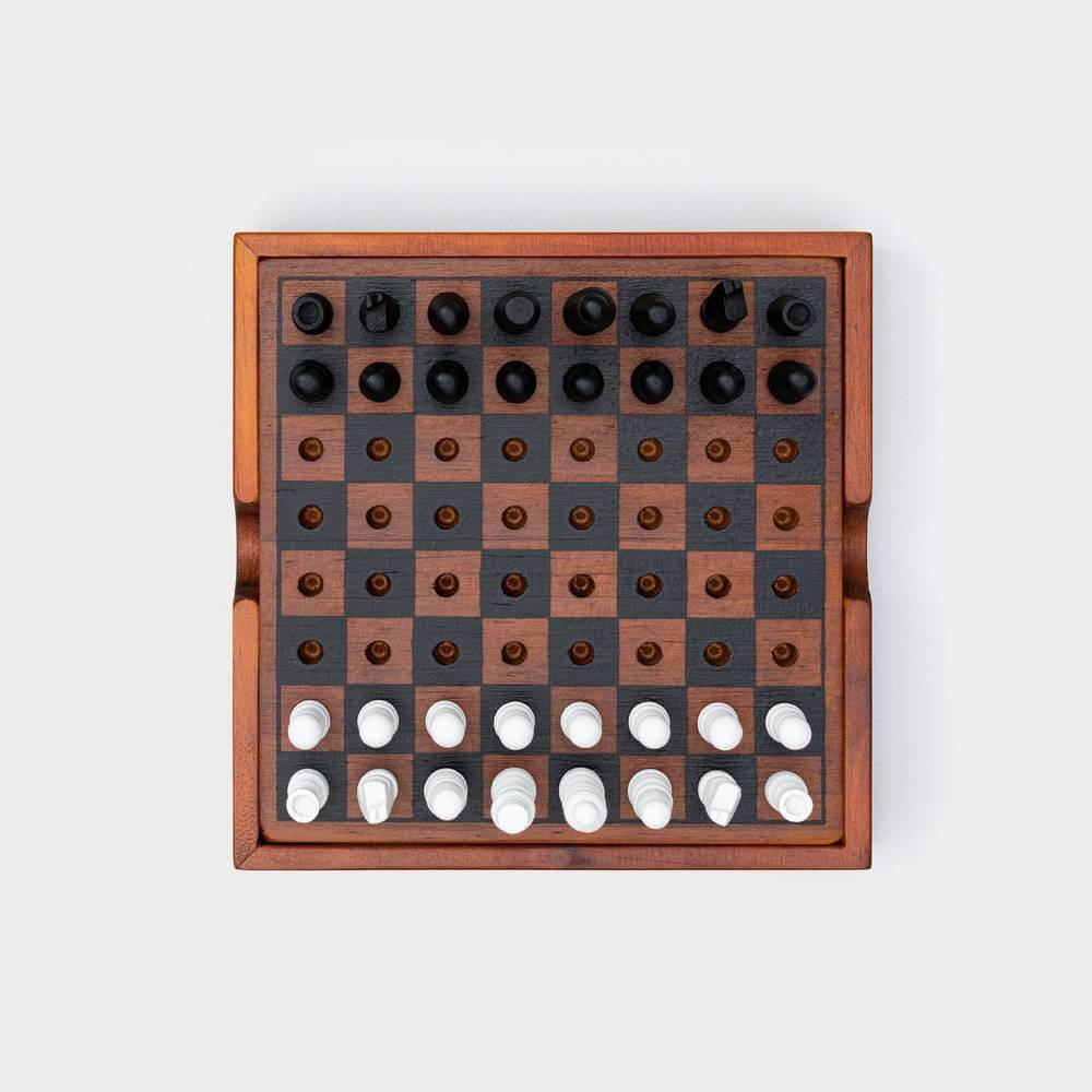 Wooden chess and checkers board with dark grid and white pieces along the bottom row