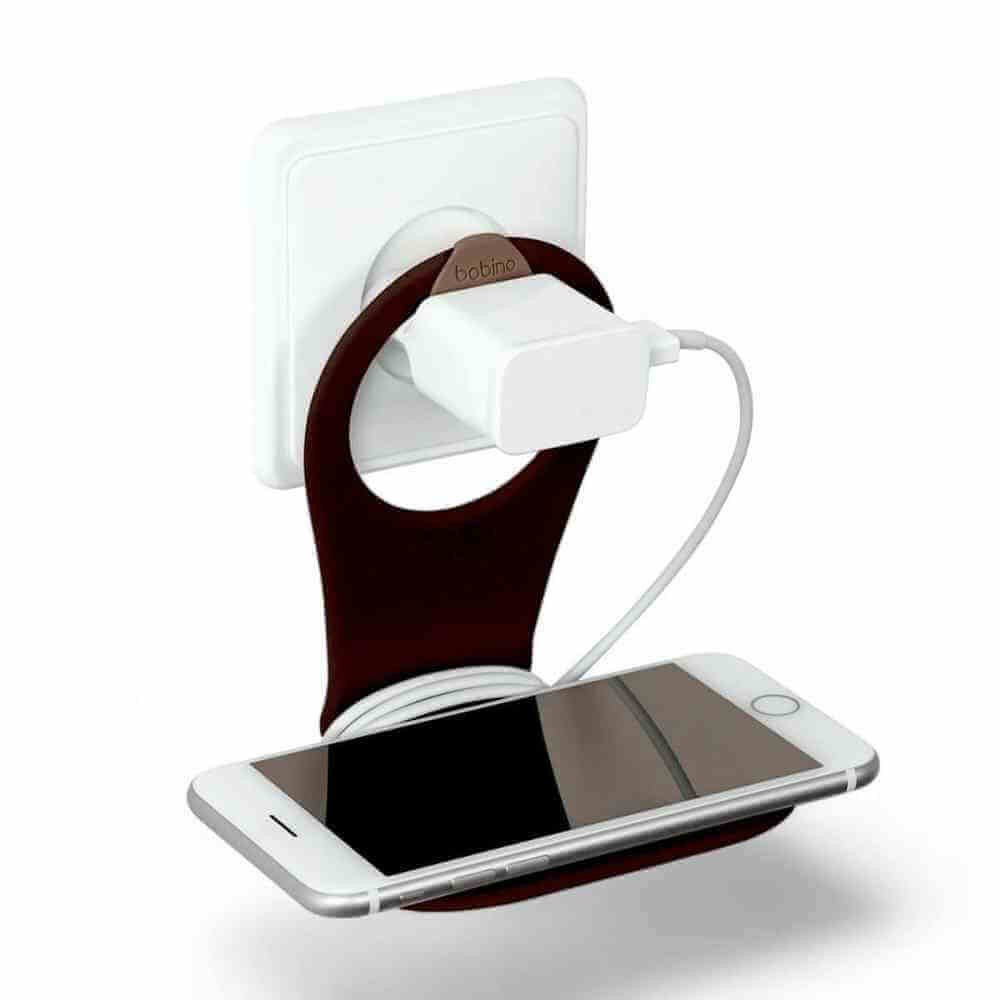Phone holder with cable tidy, dark wall mount with white cable, holding a smartphone