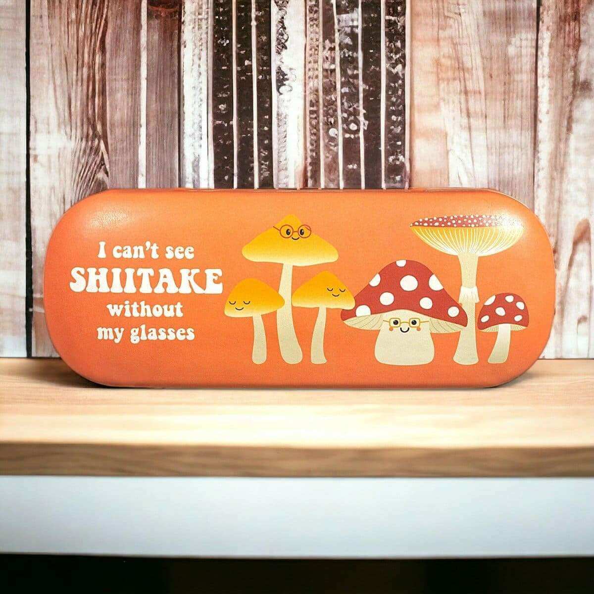 Orange mushroom-print eyeglasses case with cartoon fungi and glasses message.