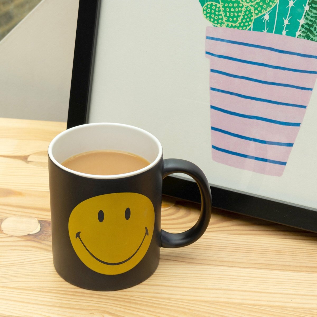 Black mug with yellow smiley face, heat-sensitive coating, side handle visible