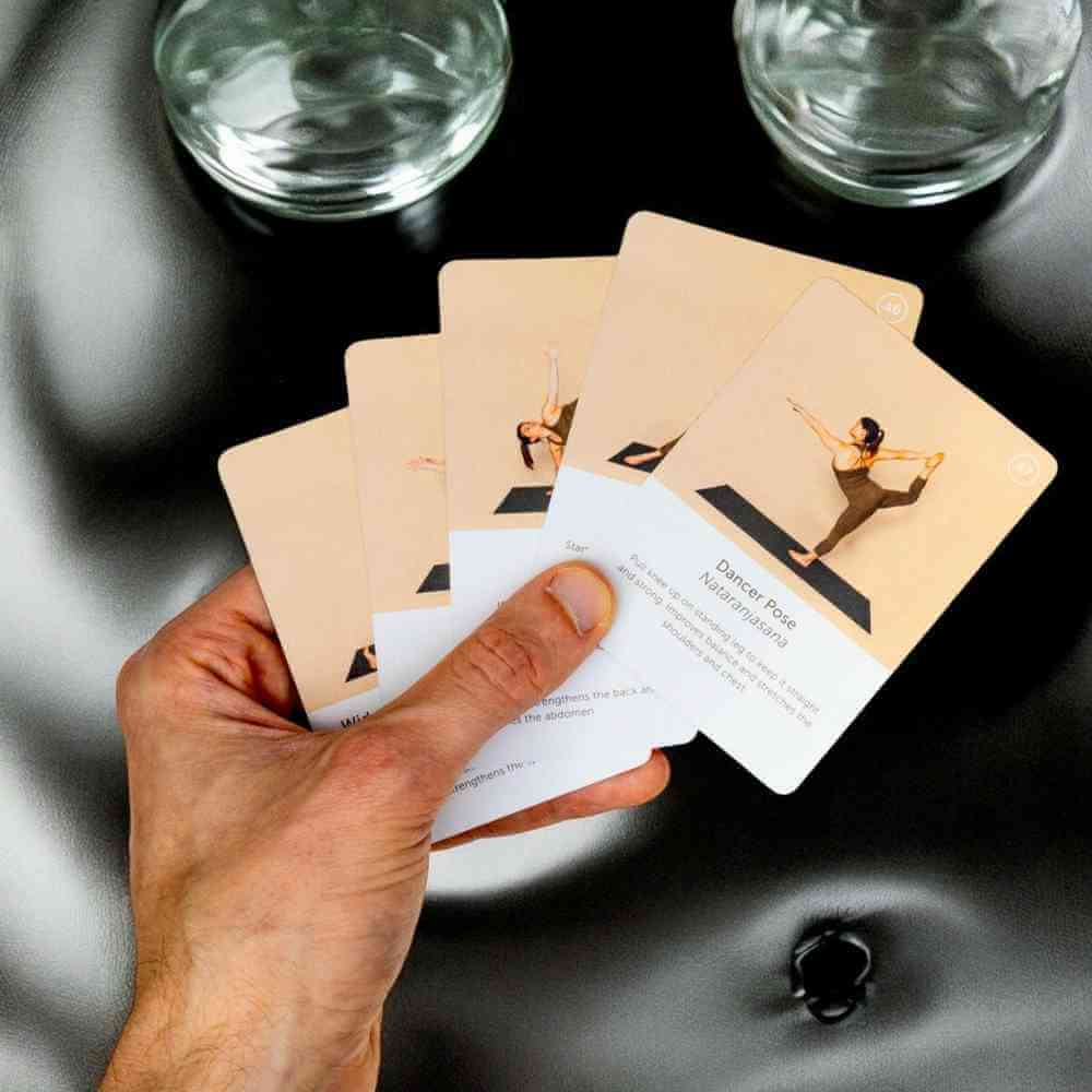 Yoga pose deck cards fanned in hand with pose instruction cards