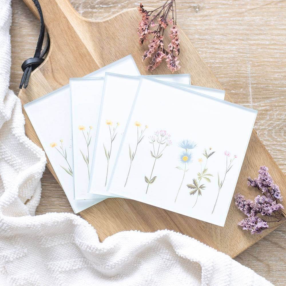 Floral glass coaster set of four on wood, pastel wildflower artwork on white tiles