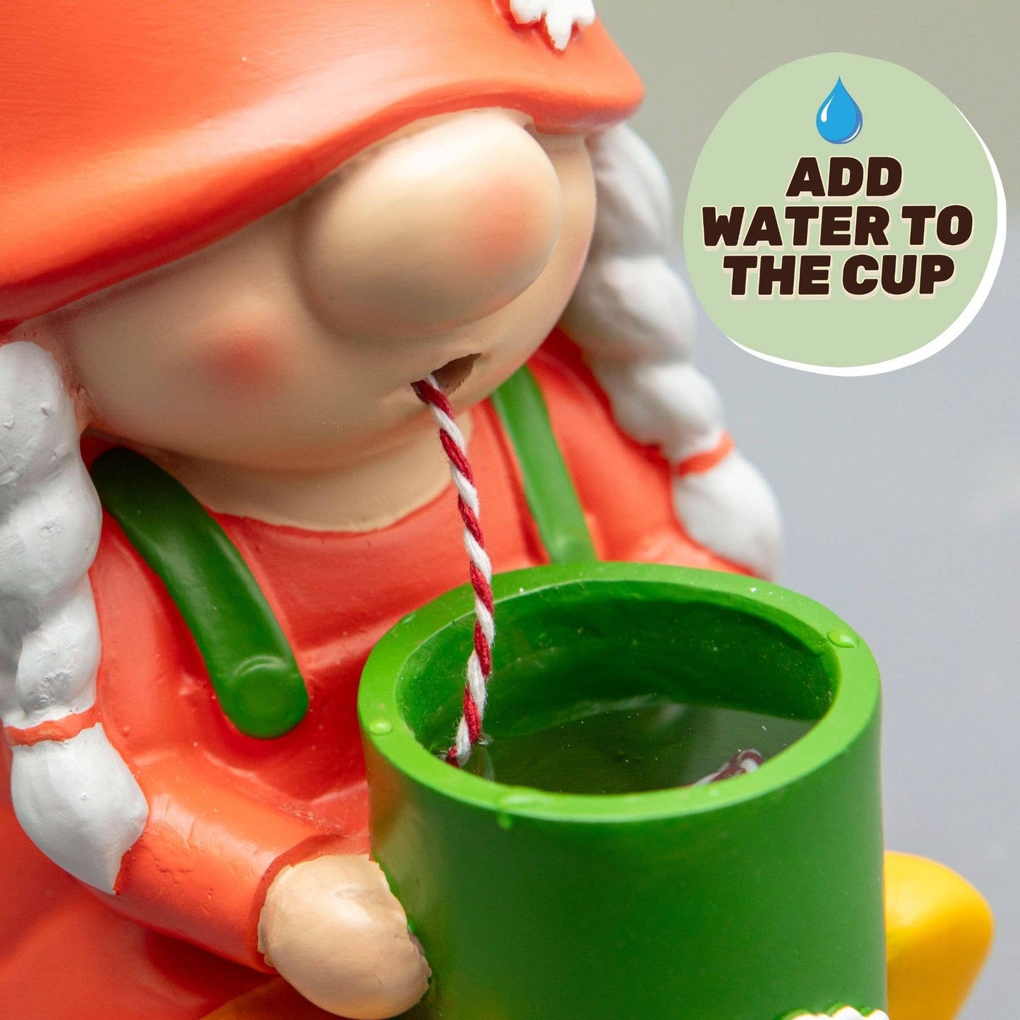 Close-up of orange gnome pouring a stream into a green self-watering cup