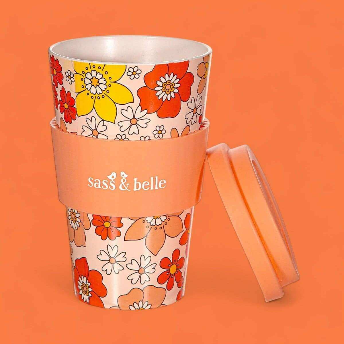 Eco reusable travel mug with orange floral sleeve, clear lid, and side carry handle; Sass & belle