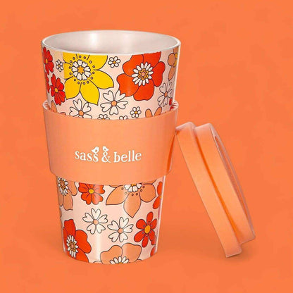 Eco reusable travel mug with orange floral sleeve, clear lid, and side carry handle; Sass & belle