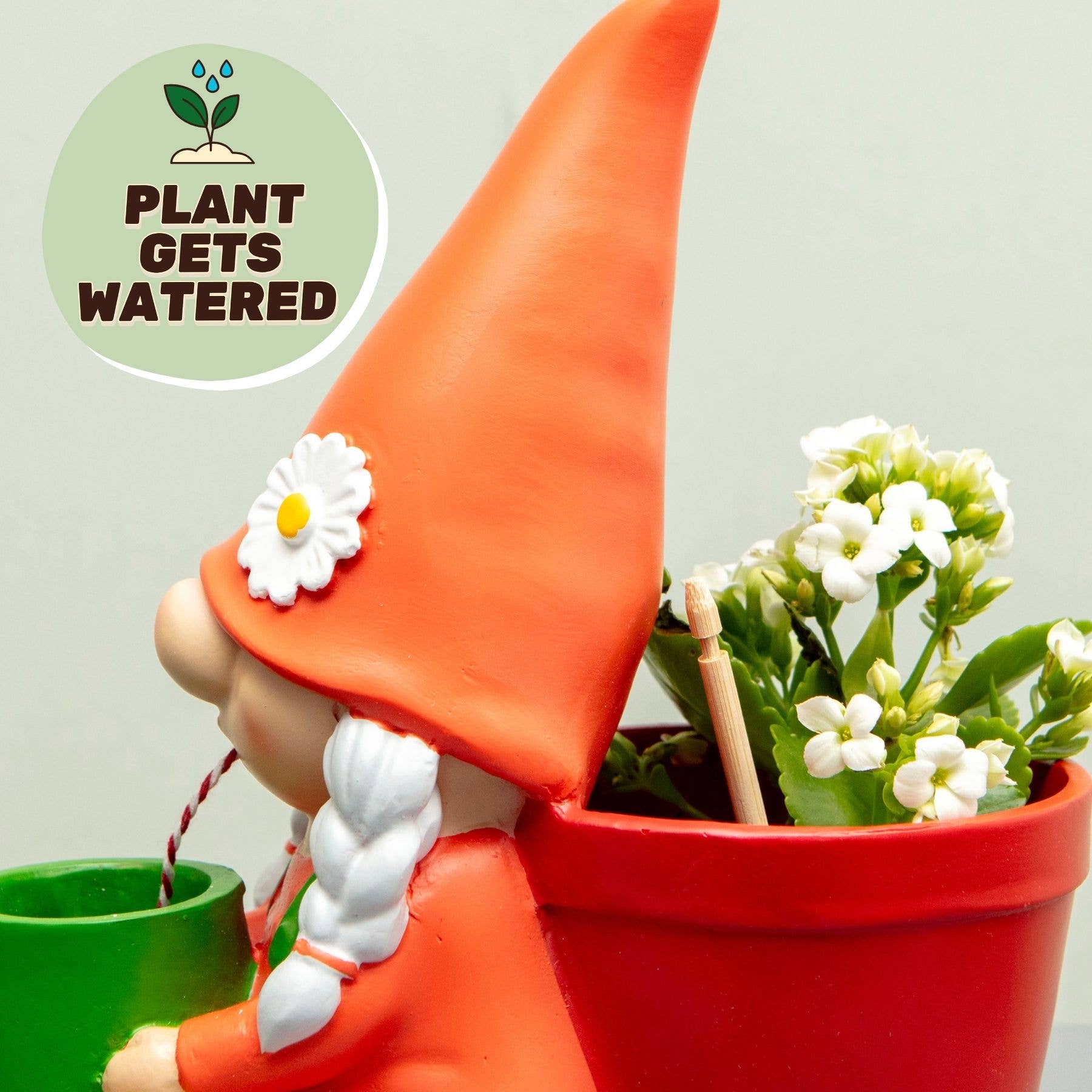 Orange gnome self-watering plant pot with red planter and white blossoms