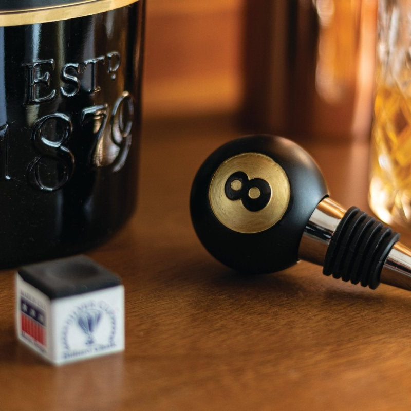 Black 8-ball bottle stopper on counter near bottles, gold 8 emblem
