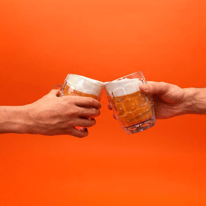 Two hands holding clear beer mugs with frothy beer