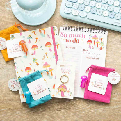 Pink Funky Fungi mushroom keyring with bronze ring, shown among stationery items