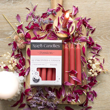 Open Spell candles carton with red unscented candles, lit wicks and purple petals