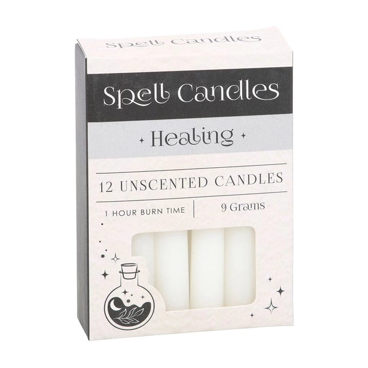 Spell candles box with 12 unscented healing candles, pale cream wax in window