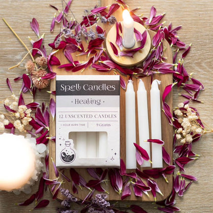 Open Spell candles carton with white unscented healing candles, lit wicks and petals