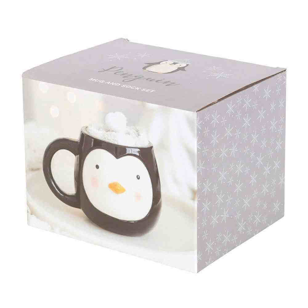 Gift set box showing a penguin-themed mug with white face and snowy socks