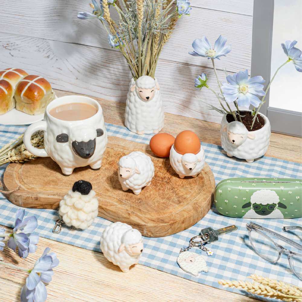 Sheep-shaped egg cups and small sheep holders on a table with eggs and pastries
