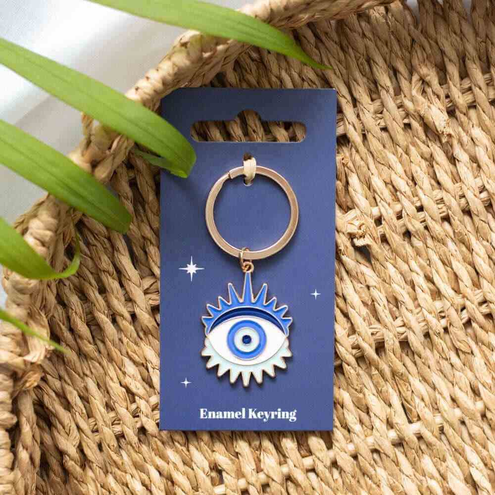 Gold metal keyring with blue enamel evil eye charm, on display card