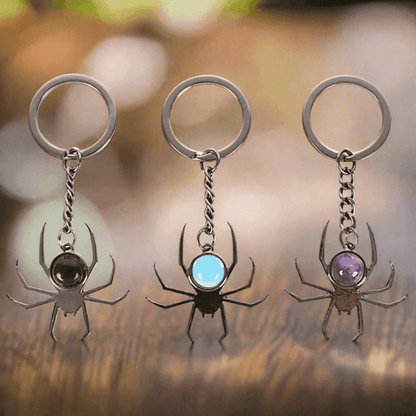 Three spider keyrings with black, light-blue, and purple round cabochon stones