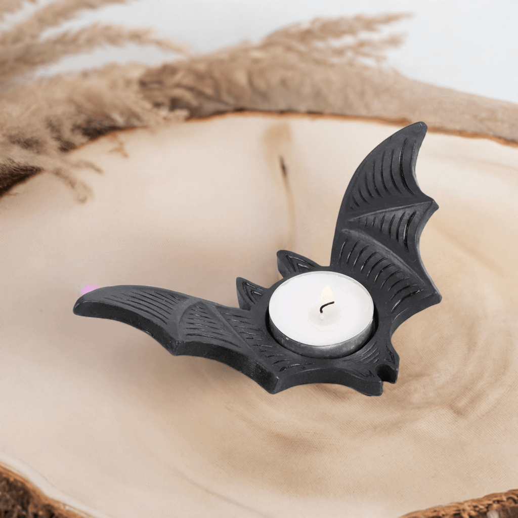 Bat-shaped tealight candle holder with white tealight candle and wick, black.