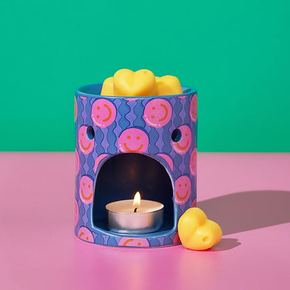 Purple patterned wax melt burner with lit tea light and yellow wax melt.