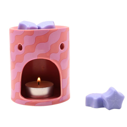 Pink wax melt burner with lit tealight in the window and lilac star wax melts