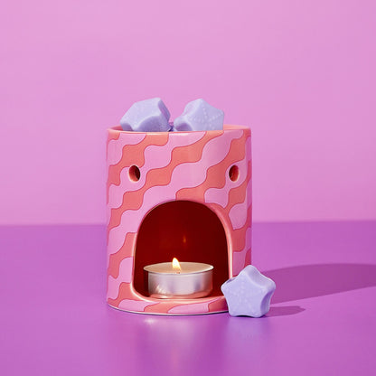 Pink wax melt burner with lit tealight and lilac star wax melts in front