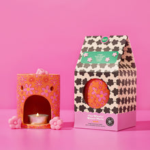 Wax melt burner with floral cutout, lit tealight, and pink wax melt pieces on top