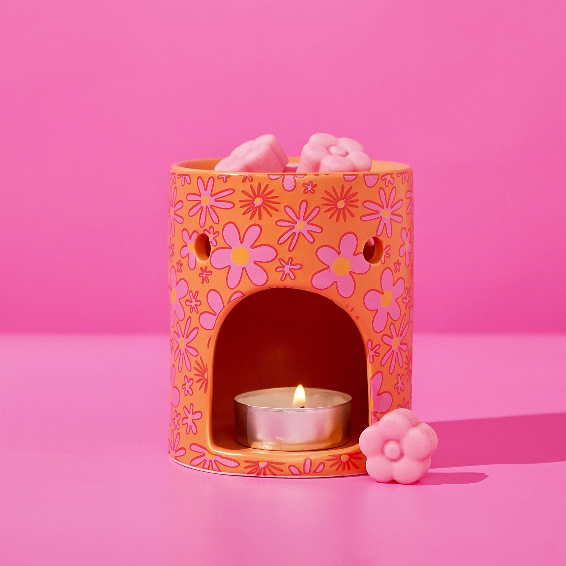 Floral wax melt burner with lit tealight and pink wax melts on top