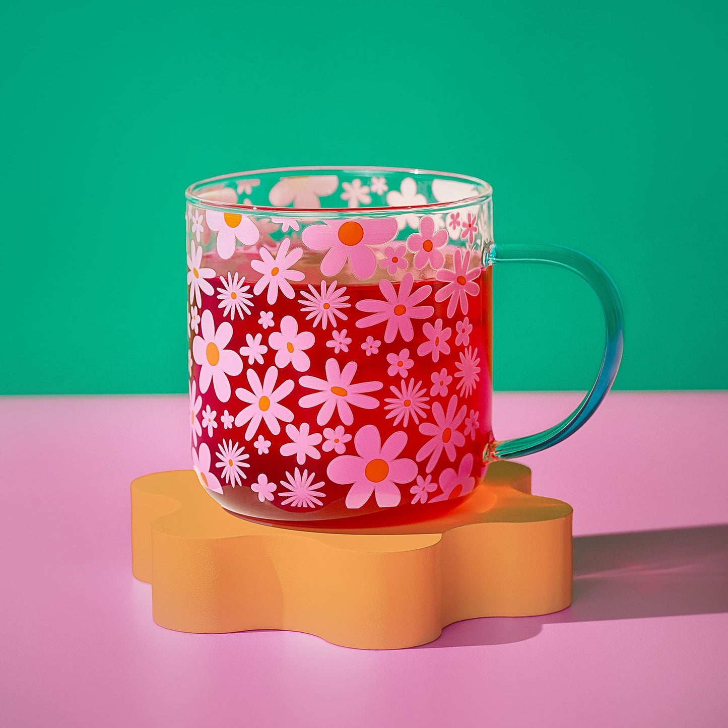 Floral glass mug with pink flowers and orange accents; mint green handle and clear body.