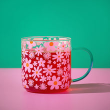Pink floral glass mug with orange and white daisies; mint green curved handle.