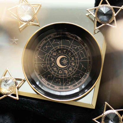 Black astrology trinket dish with gold rim and zodiac symbols in a circular layout