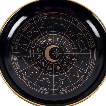 Close-up of black astrology wheel dish with gold rim and detailed zodiac ring