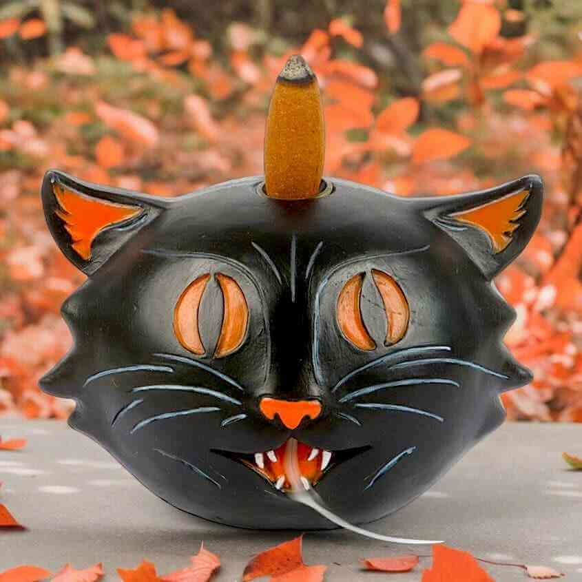 Black cat backflow incense burner with orange flames and incense cone on top