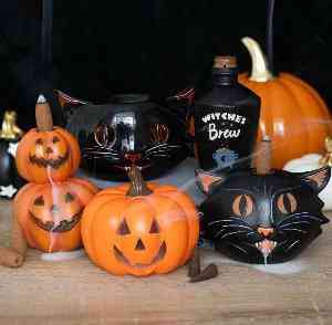 Black cat backflow incense burner with orange flame eyes and incense cone, on tray