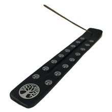 Black wooden incense stick holder with leaf pattern cutout and rows of small symbols