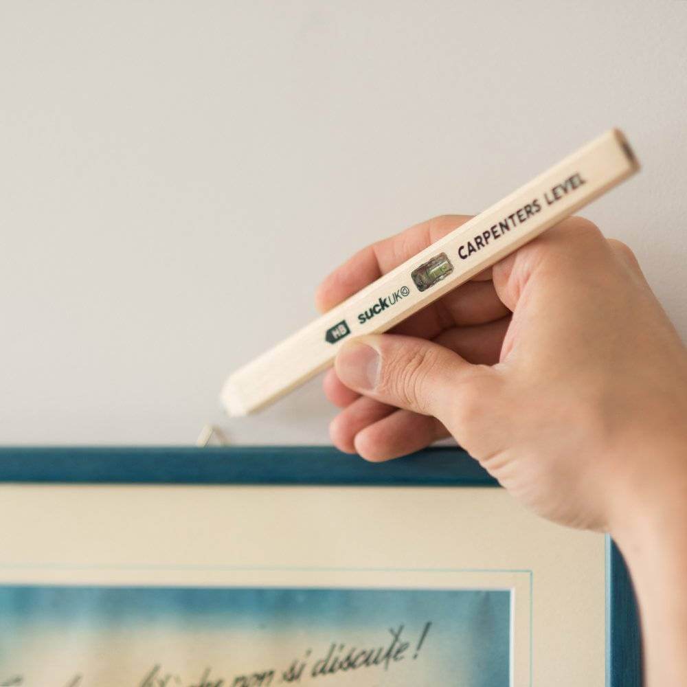 Wood carpenter's level pencil with spirit vial held near a straight edge line.