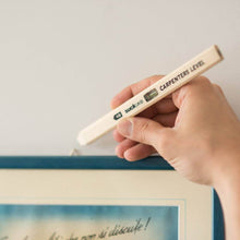 Wood carpenter's level pencil with spirit vial held near a straight edge line.