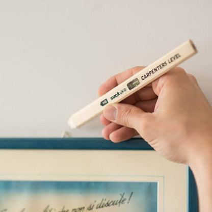 Wood carpenter's level pencil with spirit vial held near a straight edge line.