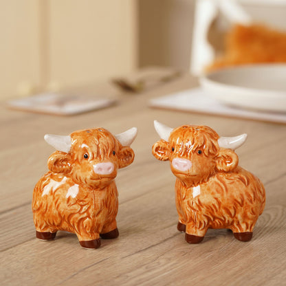 Highland cow salt and pepper shakers on wooden surface, orange-brown ceramic set
