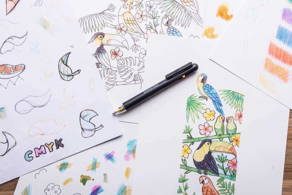 CMYK pen ballpoint near bird-and-flower sketches and colorful smudges