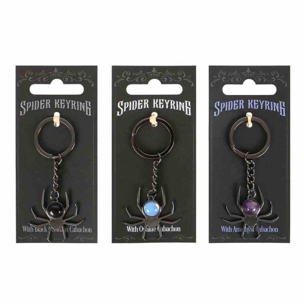 Spider keyrings on cards, showing black, light-blue, and purple round cabochon stones