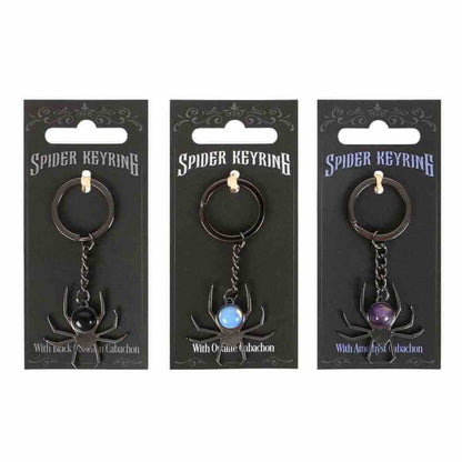 Spider keyrings on cards, showing black, light-blue, and purple round cabochon stones