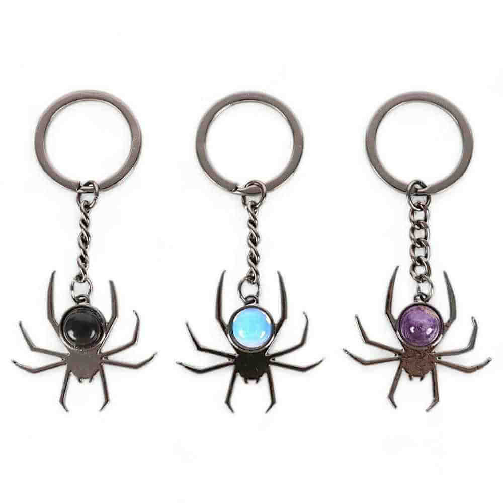 Three spider charm keyrings with black, blue, and purple round cabochon stones