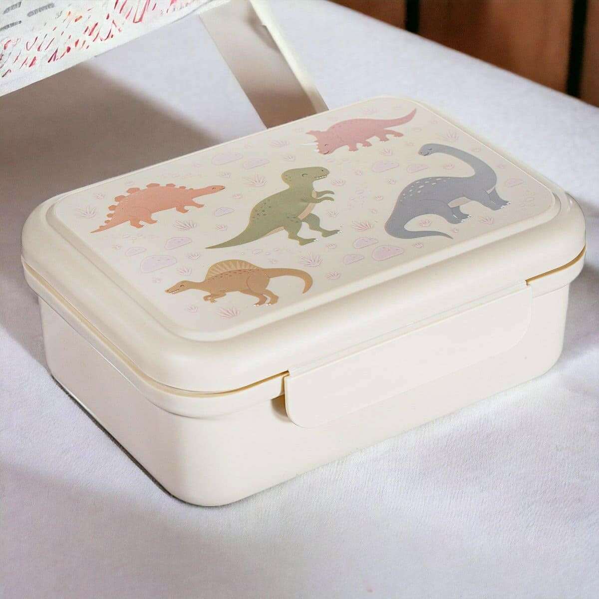 Cream kids lunch box with raised lid, dinosaur artwork, and front latch detail