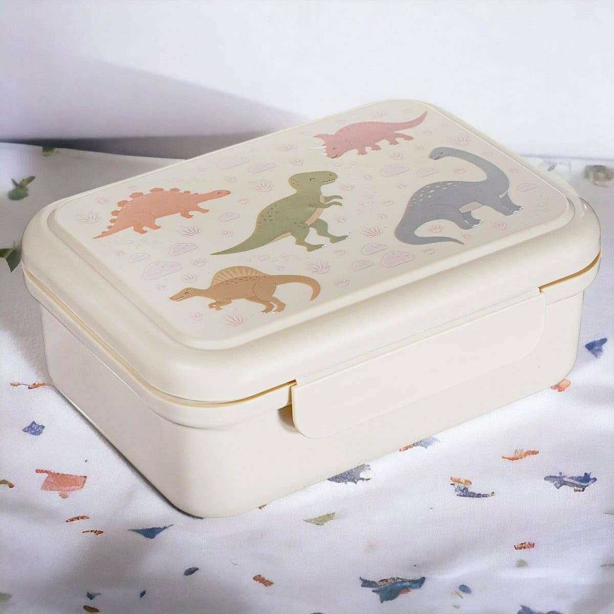 Cream kids lunch box with dinosaur graphic on lid and snap clasp front