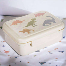 Cream kids lunch box with dinosaur graphic on lid and snap clasp front