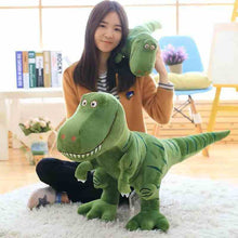 Green Tyrannosaurus Rex plush toy with long tail, held by a seated person