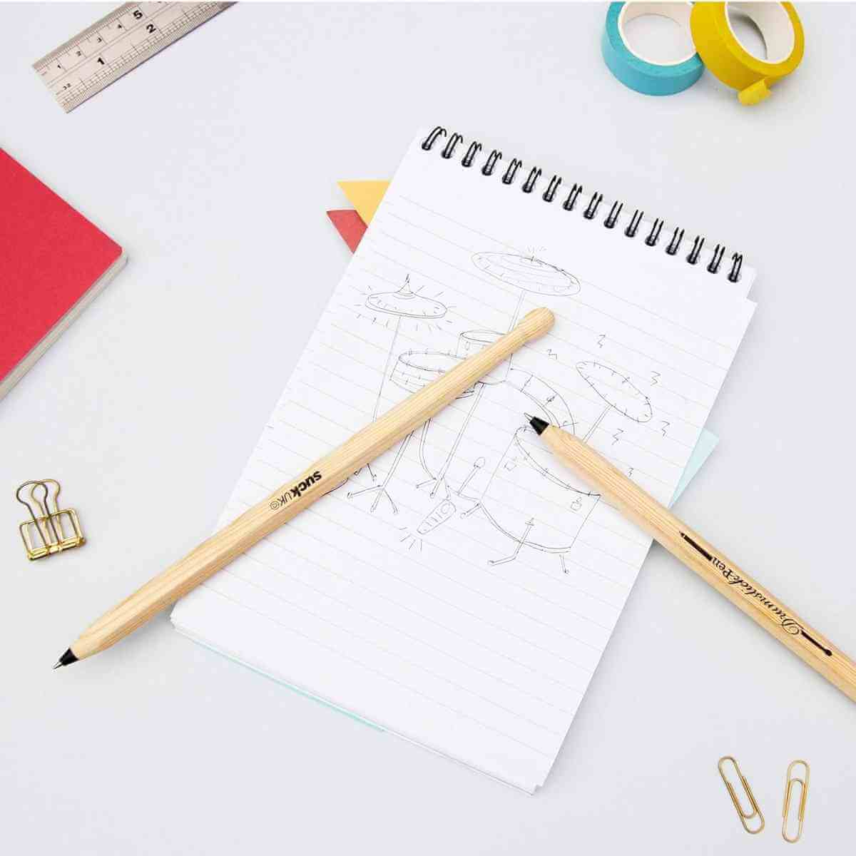 Drumstick pens set of 2 lying on sketch paper, light wood bodies with black ink tips