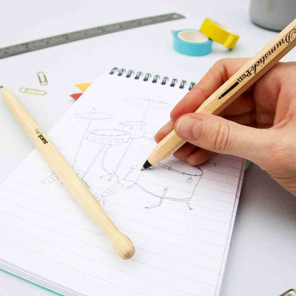 Drumstick pen set of 2, one pen held writing on a sketch page with black tip