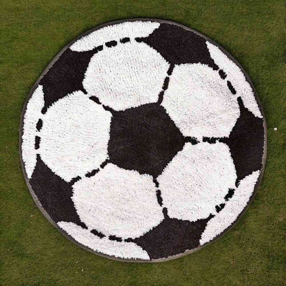 Round football-shaped rug with white soccer balls on a dark field, textured loop pile.